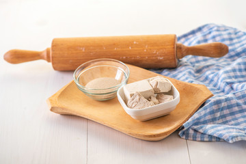 dried and fresh yeast on a white kitchen bacground with wooden rolling pin