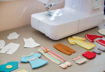 Multi-colored toy felt clothes for dolls on a table near the sewing machine