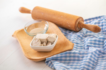 dried and fresh yeast on a white kitchen bacground with wooden rolling pin