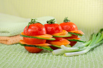 Sandwich of fresh tomato vegetables, cucumbers, carrots and feathers of green onions on a green background