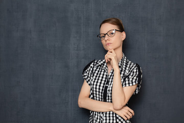 Portrait of focused girl with glasses, touching chin with hand