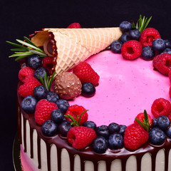  Pink and white cake with chocolate streaks, decorated with a waffle cone, raspberries, blueberries, rosemary.