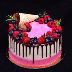  Pink and white cake with chocolate streaks, decorated with a waffle cone, raspberries, blueberries, rosemary.