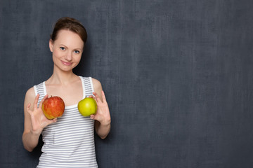 Portrait of cheerful young woman holding apples in hands over chest