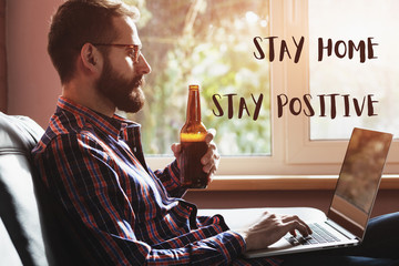 bearded man with laptop drinking bottle of beer