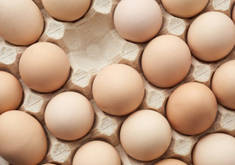 whole round raw brown homemade chicken eggs in a paper tray
