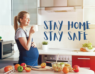 pregnant woman on kitchen making healthy fruit salad and drinking juice or tea