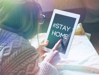 woman lying in bed with digital tablet touching with finger in morning sunlight