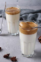Dalgona creamy coffee in a glass on a light gray background with whipped foam. Korean coffee trend, Vertical format