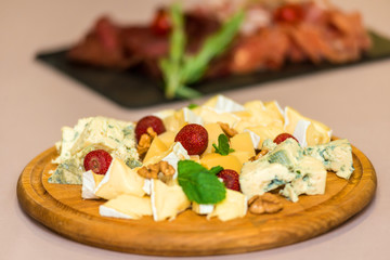 assorted cheeses with strawberries on a wooden tray. horizontal frame
