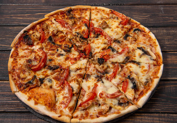 Pizza with mushrooms and chicken on a wooden table.