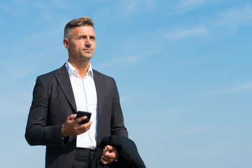 Mobile communication. Successful and motivated business man. Businessman well groomed hairstyle. Make decisions on the go. Business concept. Business life. Man classic style blue sky background.