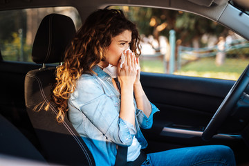 Young woman driving car with protective mask on her face.  Healthcare, virus protection, allergy...