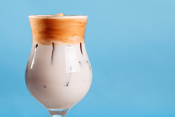 Iced Dalgona Coffee, a trendy fluffy creamy whipped coffee on a bright blue background. new trends in coffee