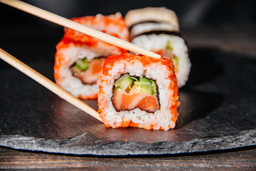 Beautiful and delicious variety of sushi rolls laid out on a stone board.