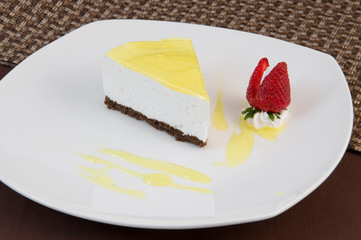 A slice of cake made of thin chocolate biscuit and whipped cream souffle with lemon caramel decorated with meringues and strawberries