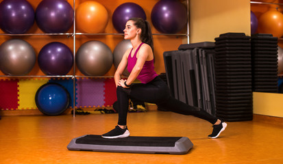 Young sportive woman exercising in gym using step platform