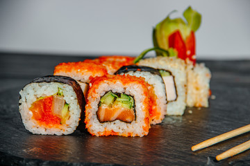 Beautiful and delicious variety of sushi rolls laid out on a stone board.