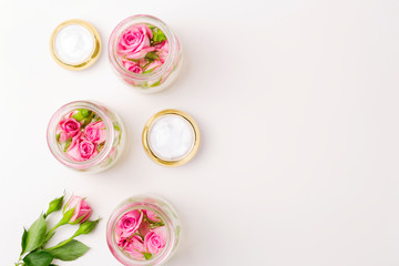 Homemade spa with rose cosmetic cream on pink background top view