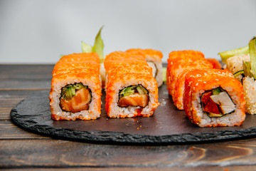 Beautiful and delicious variety of sushi rolls laid out on a stone board.