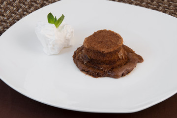 Chocolate cake with a slice of ice cream on one plate on a brown background