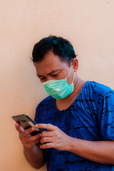 Fototapeta premium Asian man wearing face mask is showing head ache expression. The concept of people having to wear masks in public during a COVID-19 pandemic or coronavirus disease crisis.
