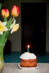 a vase of flowers and a holiday cake with a candle on the table
