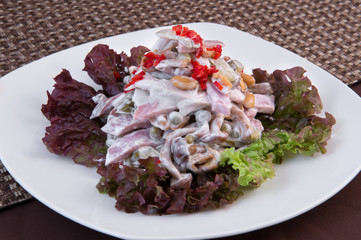 A salad of ham, mushrooms, green pickled peas, pickled cucumber, seasoned with mayonnaise, decorated with lettuce and finely chopped red pepper