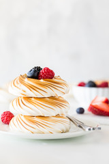 A close up view of a stack of toasted meringues in a stack with berries on top.