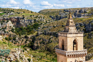 San Pietro Caveoso bell tower against the blurred Matera canyon landscape in Matera, Province of...