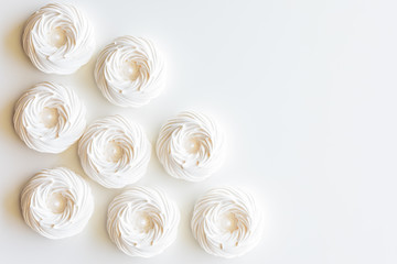 A top down view of several merengue cookies against a white background with copy space to the right.