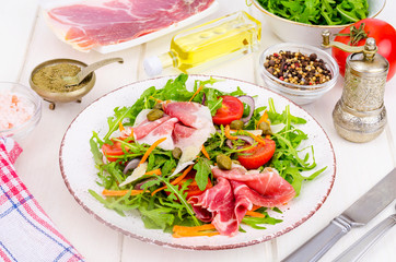 Fresh homemade salad with arugula, jamon, rucola, tomatoes, parmesan.