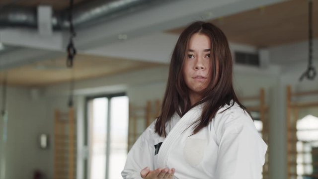 Young woman practising karate indoors in gym.