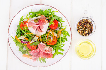Fresh homemade salad with arugula, jamon, rucola, tomatoes, parmesan.