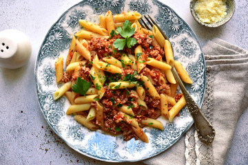 Penne pasta with bolognese sauce - traditional recipe of italian cuisine. Top view with copy space.