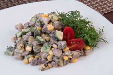 Salad of pieces of meat, mushrooms, a tin of canned corn, cucumbers, as well as tomatoes, parsley and dill for decoration