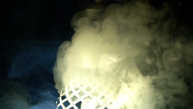A close-up of the hookah finds thick light smoke on a black background, slow motion