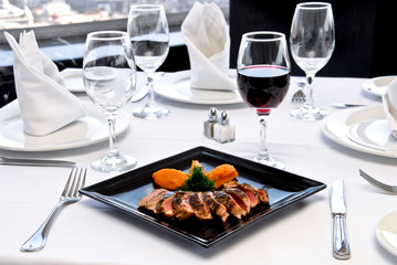 plato de lomo mechado con copa de vino tinto sobre una mesa de restaurante, con mantelería blanca