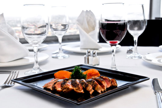 plato de lomo mechado con copa de vino tinto sobre una mesa de restaurante, con manteler&iacute;a blanca