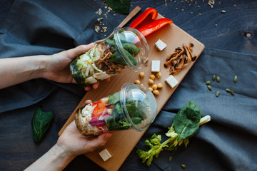 hands holding glasses of salad