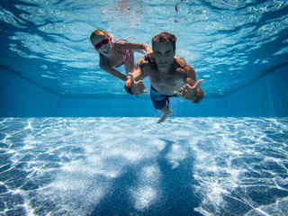 Father and daughter underwater in pool