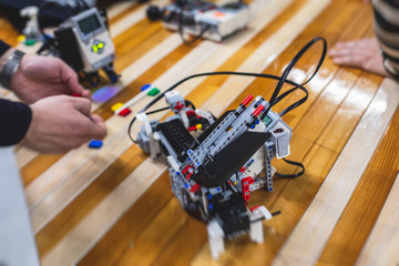 Group of children kids playing with robotic vehicle model, science lesson, making and programming a handmade robot, robotics projects, fun and development