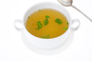 Transparent meat broth with herbs in white plate