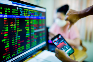 Stock exchange market business. Display of Stock market quotes with blurry red graph on smartphone and the patient is wearing a mask. The concepts of the economic downturn from Covid 19.