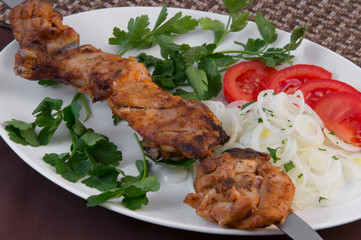 Charcoal slices on a stick baked on charcoal, tomatoes, onion rings, parsley