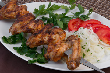 Charred chicken sticks on a stick with tomatoes, parsley and onion, cut into rings