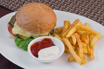 Hamburger with beef patty, tomatoes, pickles, lettuce, french fries and sauce
