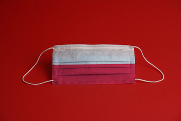 Coronavirus protective mask. Medical mask combined with the flag of Poland. Red background. Face...