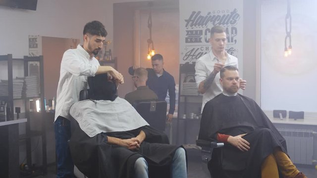 Barbershop room with clients in chairs and hairdressers working