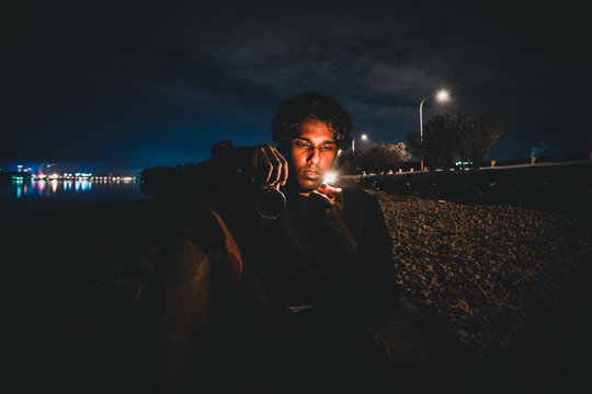 Man Holding Cigarette Lighter At Beach During Night